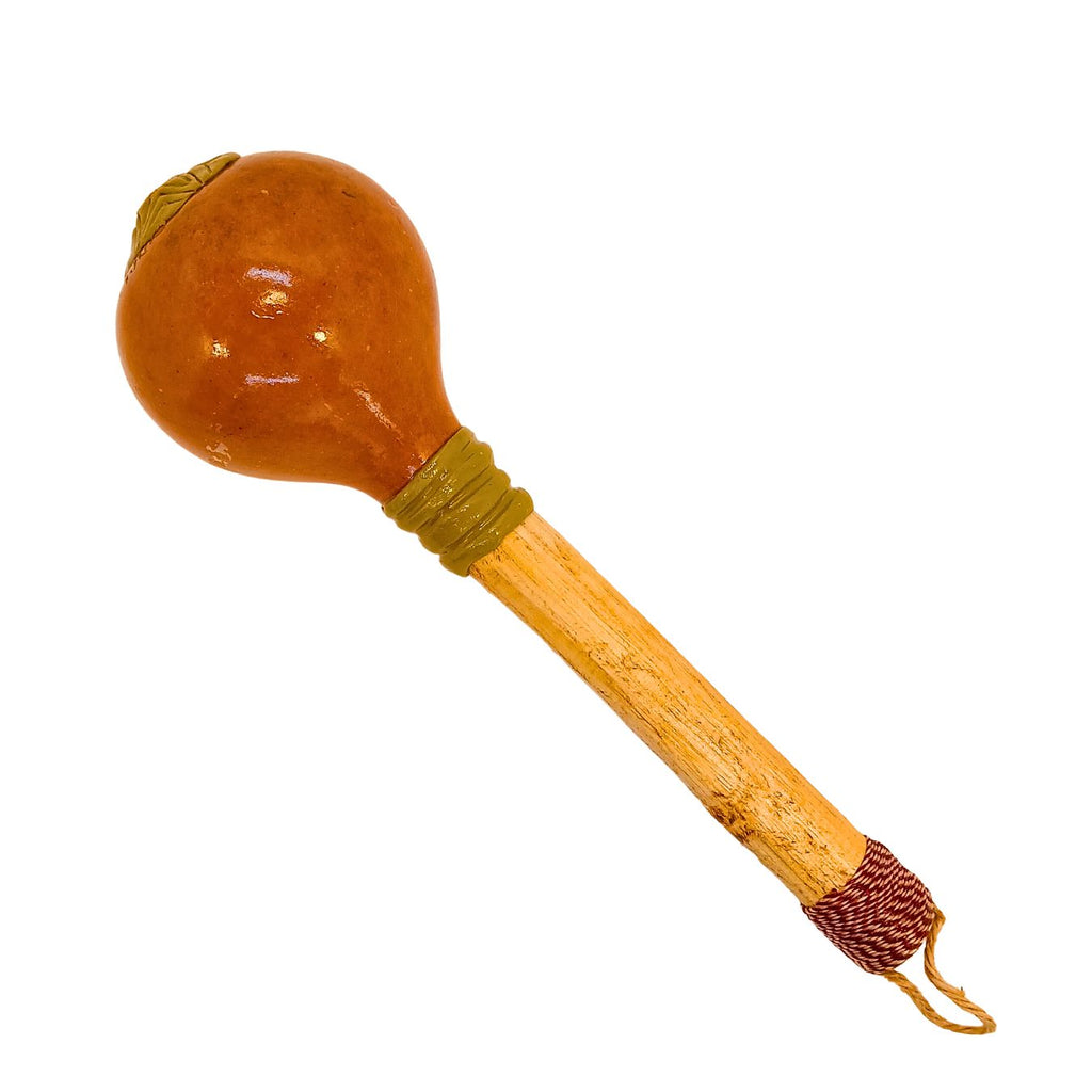 Maraca de cabaça com cabo de madeira e laço na ponta, cor marrom-dourada.