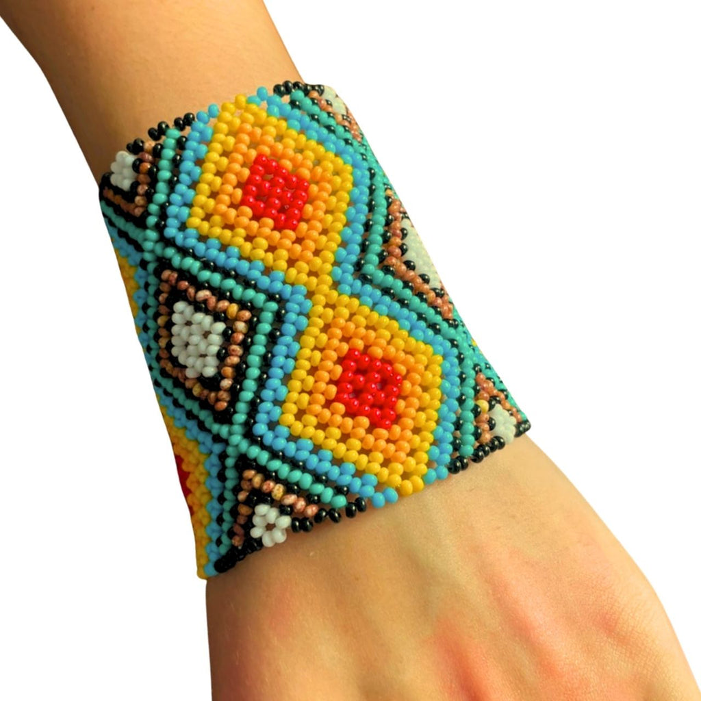 Pulseira de miçangas multicolorida no pulso, com padrão geométrico em azul, amarelo e vermelho