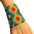 Pulseira de miçangas multicolorida no pulso, com padrão geométrico em azul, amarelo e vermelho