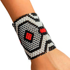 Pulseira de miçangas elástica com padrão preto, branco e detalhes vermelhos