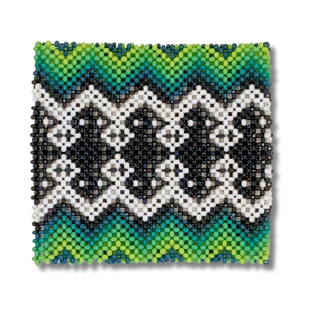 Pulseira de miçangas indígena, bordado zigue-zague branco e preto com base verde e azul.