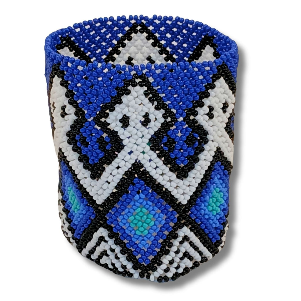 Pulseira de miçangas azul com grafismos pretos e brancos, formato geométrico.