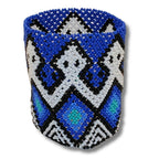 Pulseira de miçangas azul com grafismos pretos e brancos, formato geométrico.