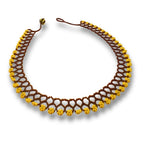 Colar de miçangas com trama em losangos marrom e dourado, com fecho de cordão vermelho