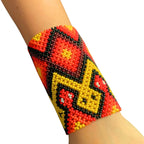 Pulseira de miçangas elástica com padrão geométrico vermelho, amarelo e preto.