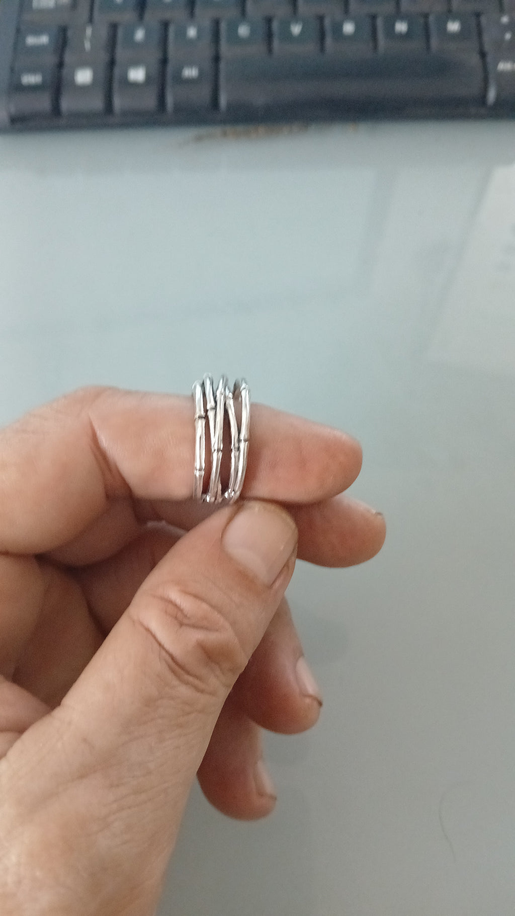 Anel prateado em três voltas finas com detalhes ranhurados no aro
