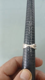 Anel de metal prateado com três faixas ranhuradas e acabamento refletivo
